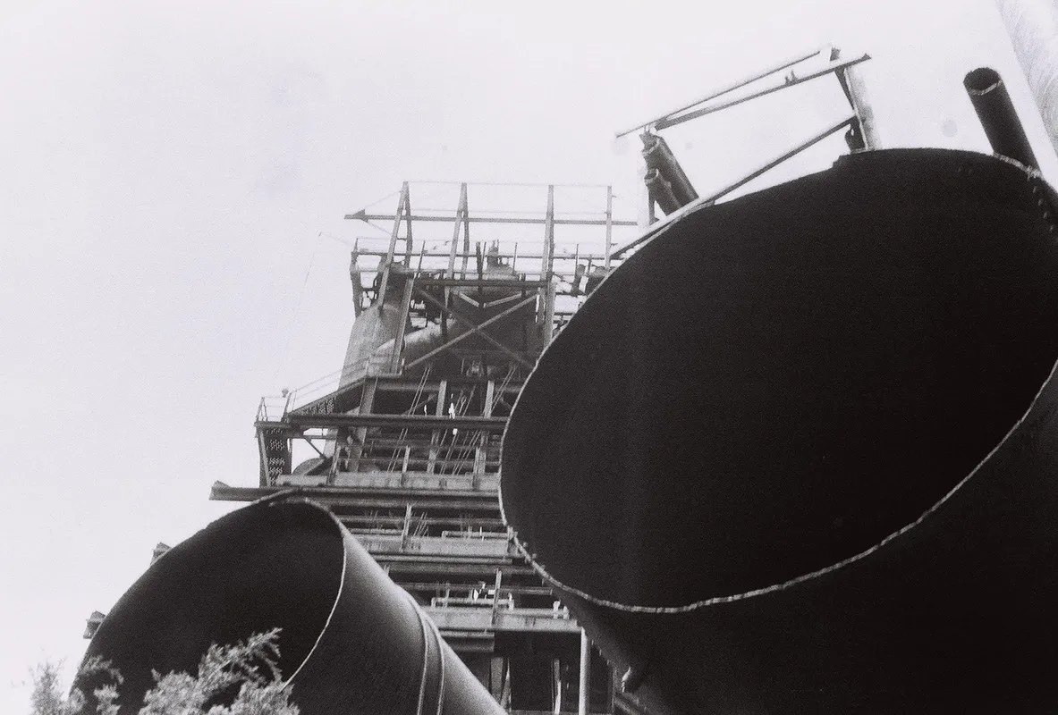 rusty metal tower partially obscured by pipes in foreground