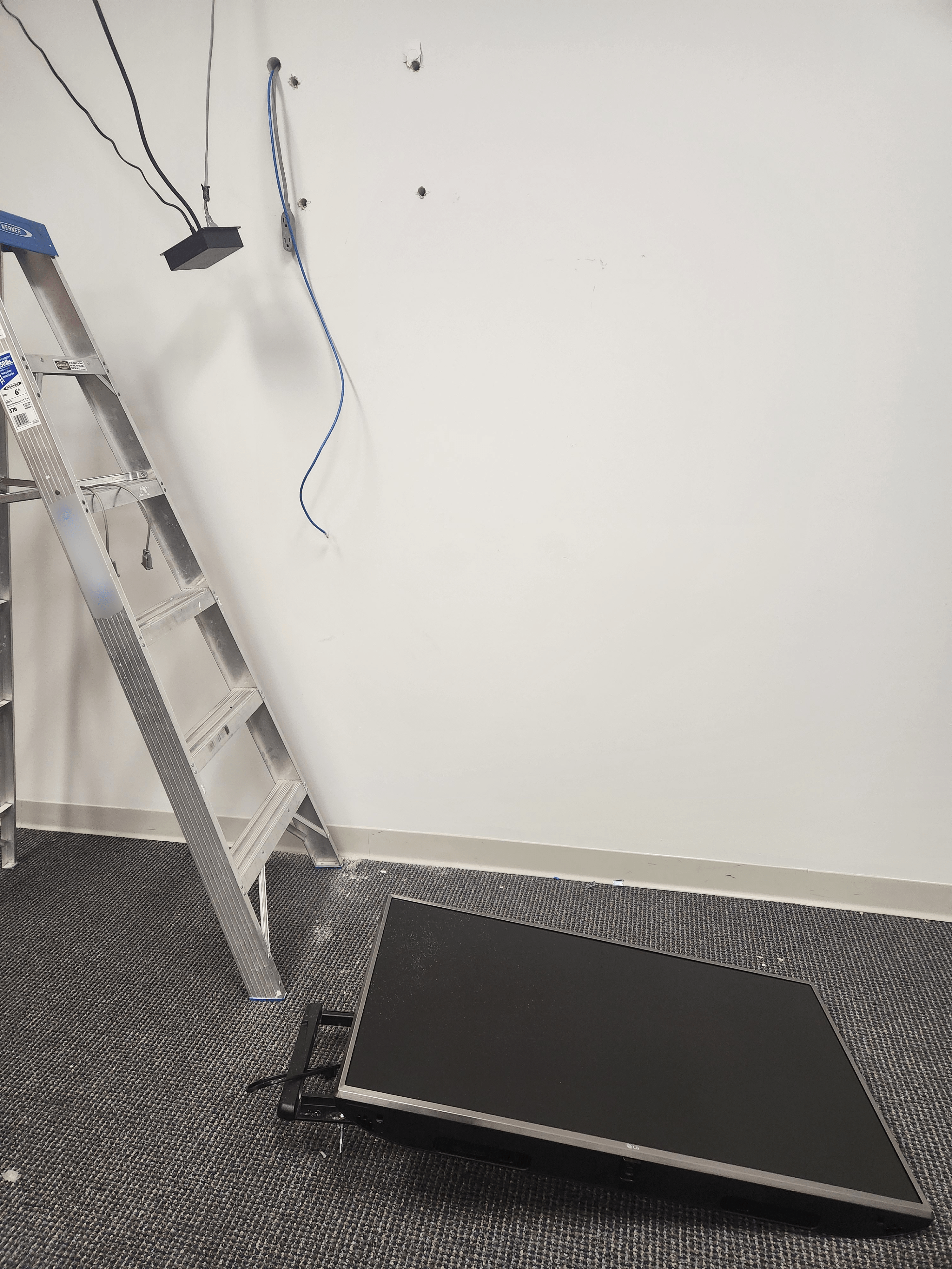 A flatscreen TV on the ground next to a ladder