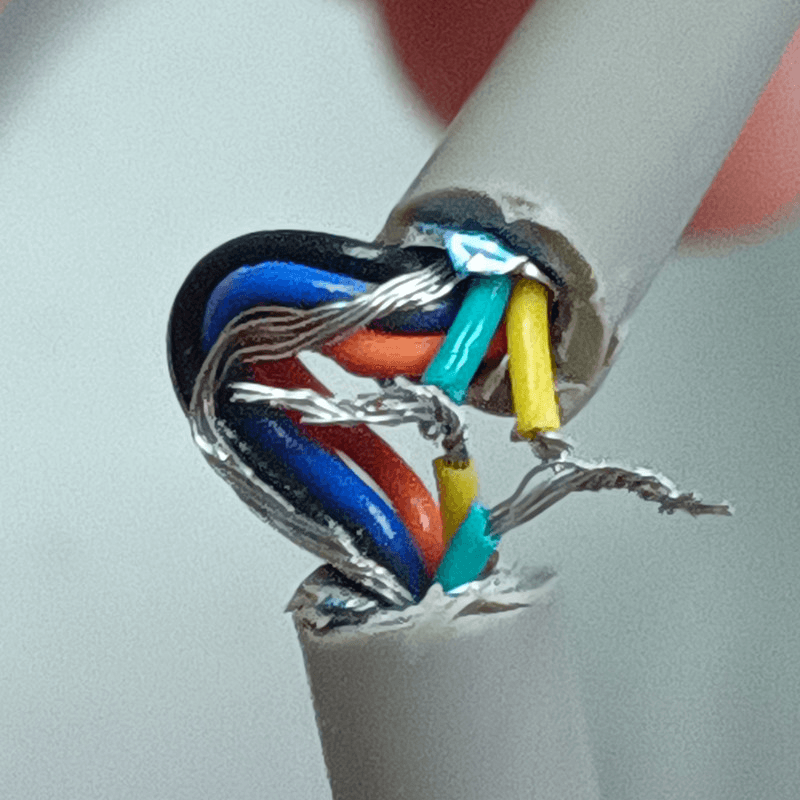 A serial cable with a section cut out, exposing its wires. Two of the wires have been severed and re-attached.