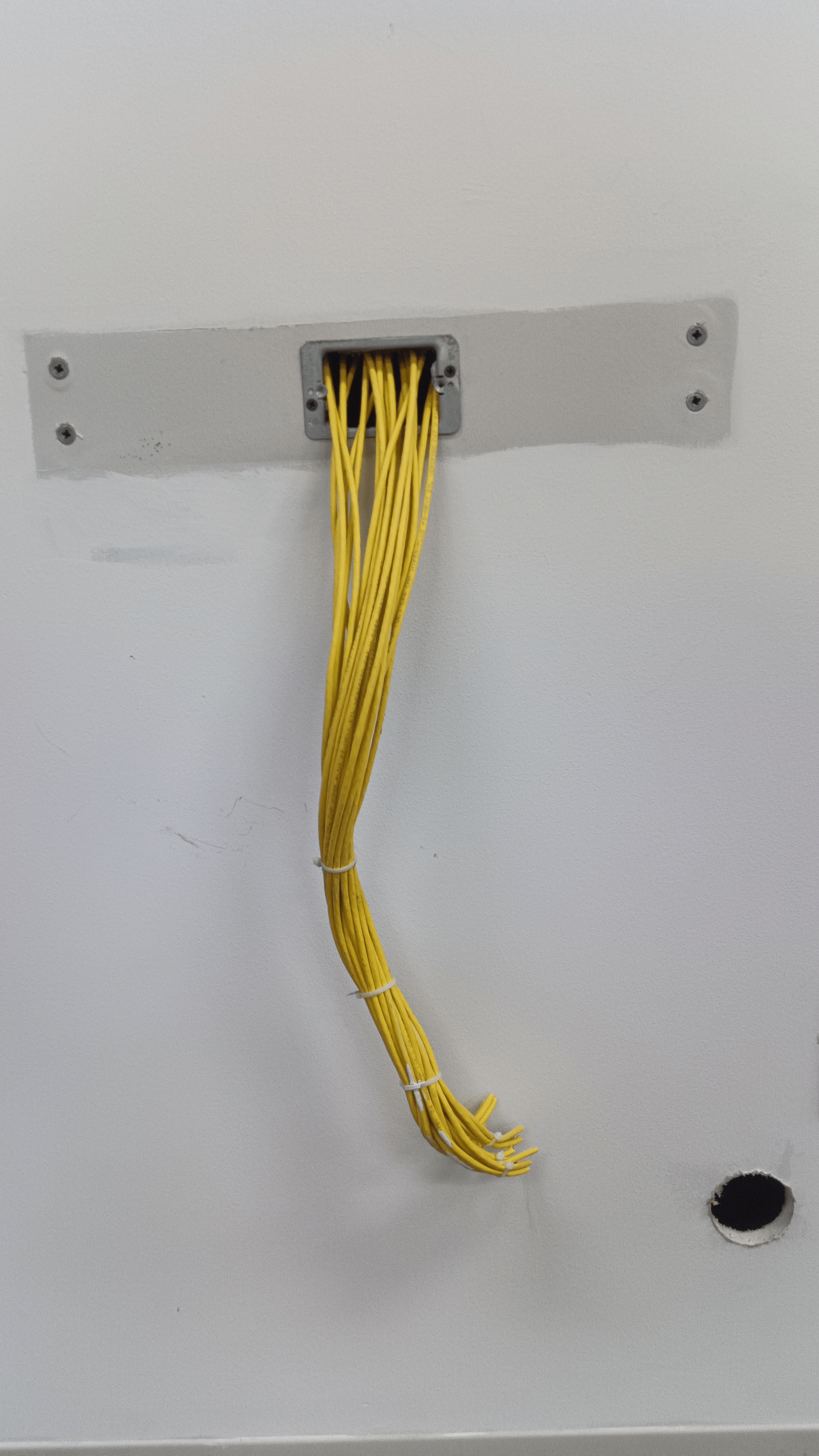 A bundle of yellow cables spilling from a wall outlet