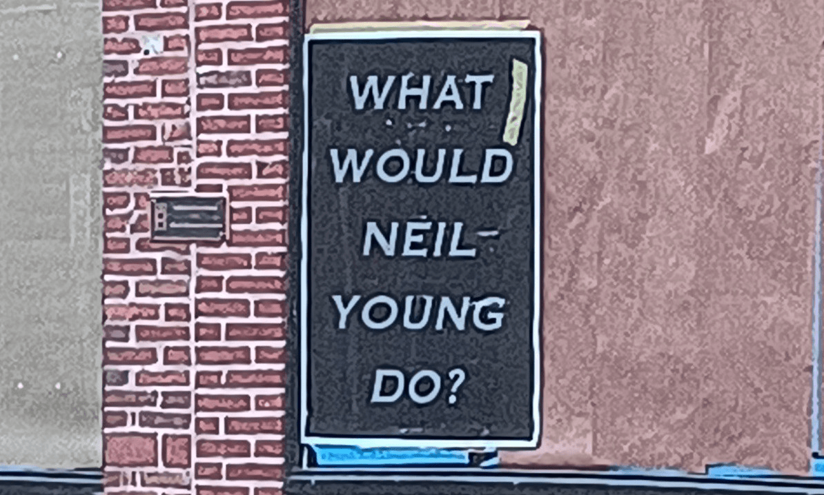 A poster on a building that says, "WHAT WOULD NEIL YOUNG DO?"