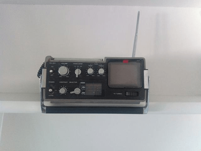 An apparatus sitting on a shelf with knobs and dials and a built-in TV screen
