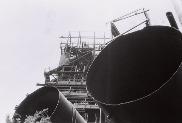 rusty metal tower partially obscured by pipes in foreground