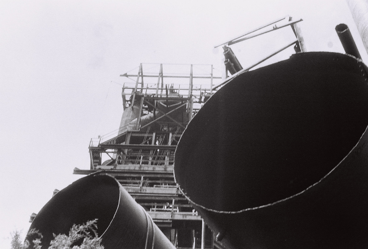 rusty metal tower partially obscured by pipes in foreground